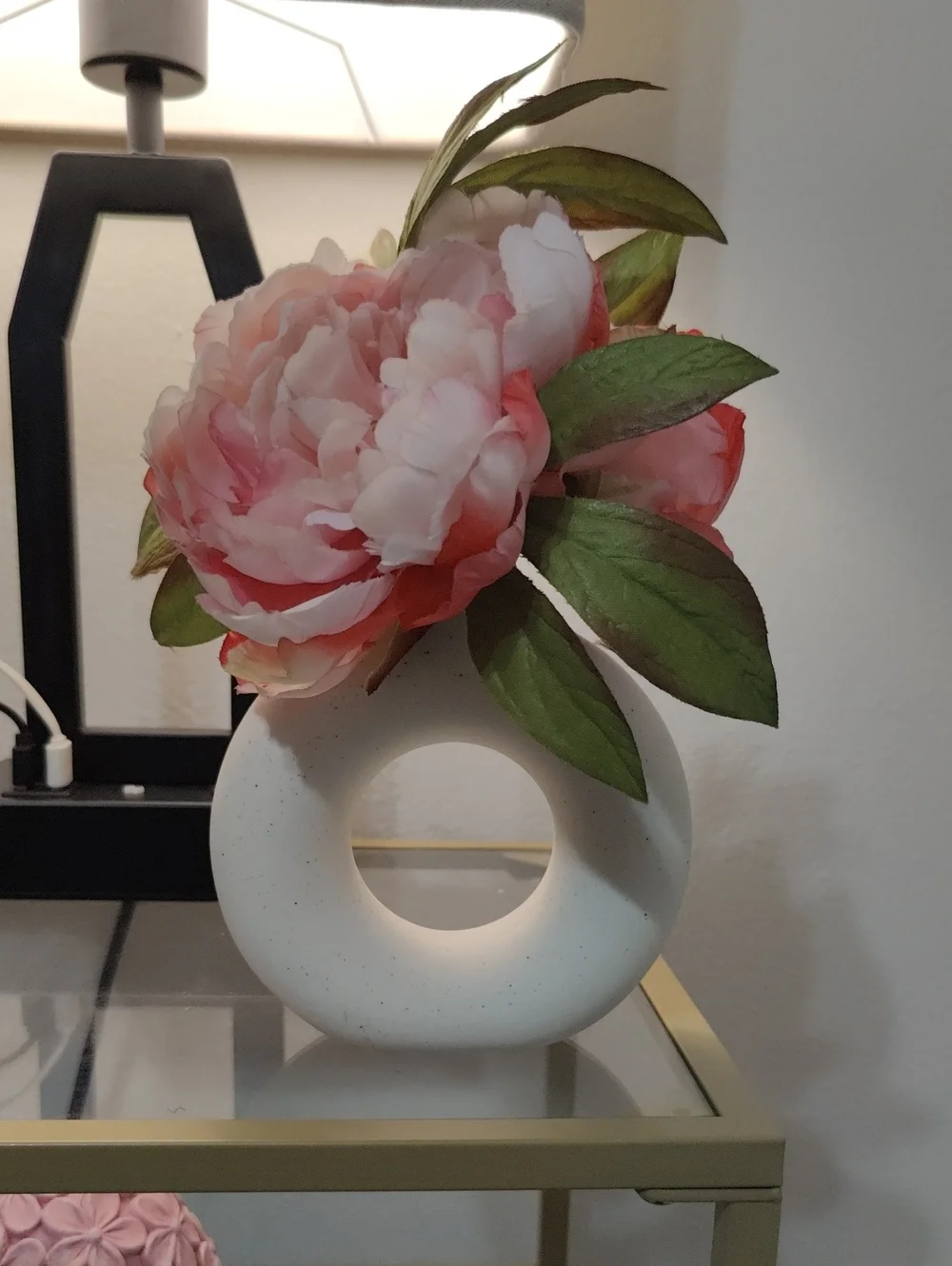 White Donut Ceramic Vase with Beautiful Pink Peony Flowers and Green Leaves.